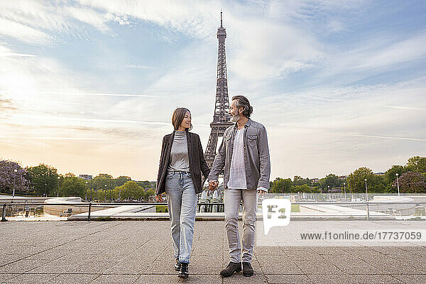 Happy mature couple holding hands walking in front of Eiffel Tower  Paris  France