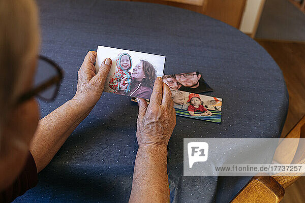 Lonely senior woman holding family's photograph at table
