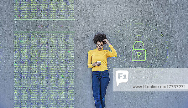 Confused woman looking at smartphone with data lock painted on wall