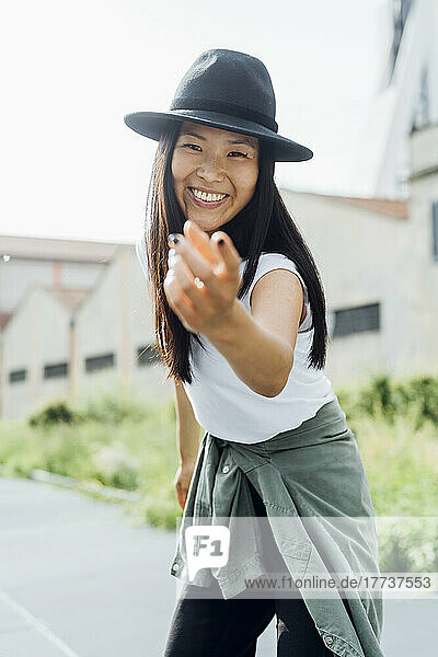 Happy young woman wearing hat gesturing enjoying dance on sunny day