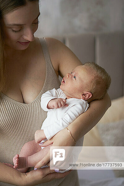 Woman holding cute baby son at home