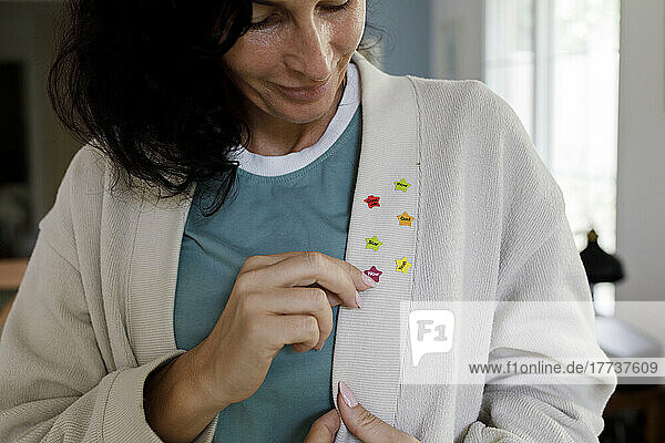 Smiling woman looking at star stickers on cardigan sweater
