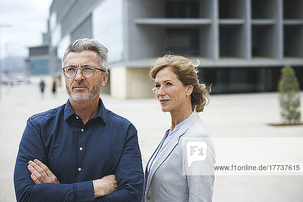 Businessman with arms crossed standing by businesswoman