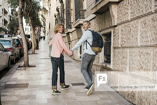 Lächelndes reifes Touristenpaar  das im Urlaub auf dem Fußweg spaziert