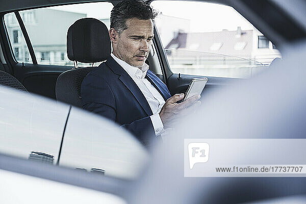 Businessman using smart phone sitting in car