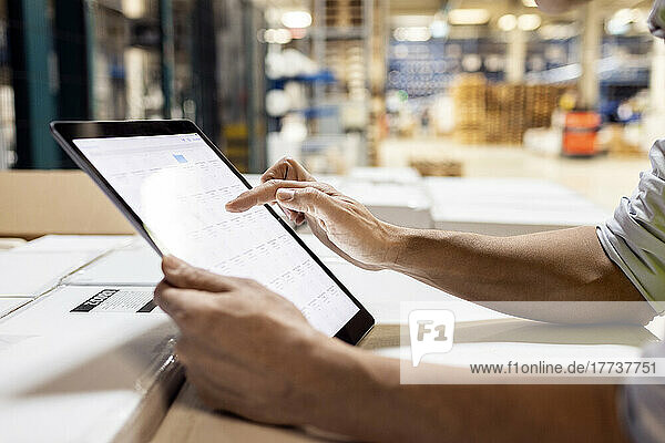 Hands of worker using tablet PC for checking inventory working in warehouse