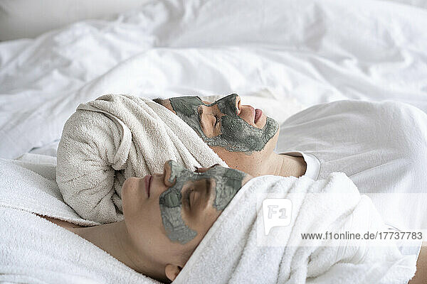 Freunde mit Gesichtsmasken liegen zu Hause im Bett