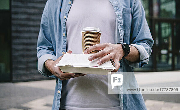 Man holding disposable cup and lunch box
