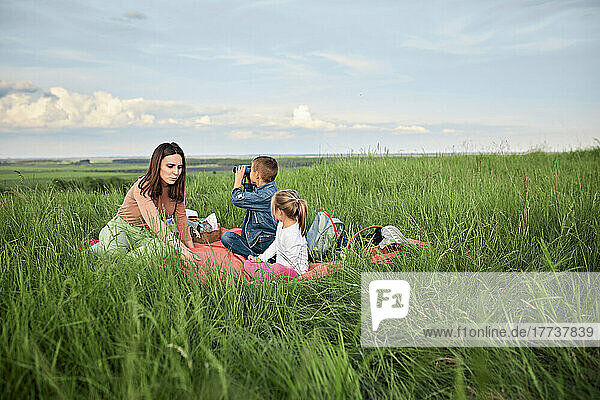 Mother with children sitting amidst grass in field