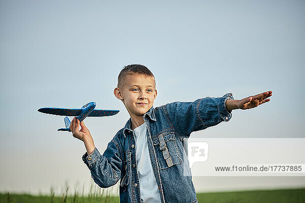 Boy holding toy airplane in field