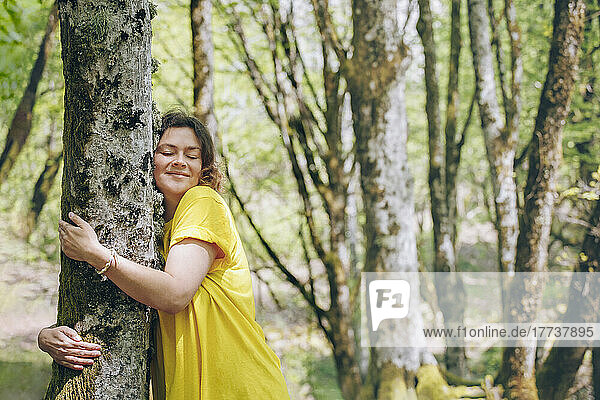 Woman hugging tree in forest on vacation