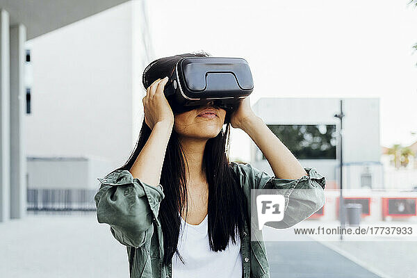 Junge Frau mit schwarzen Haaren trägt einen Virtual-Reality-Simulator