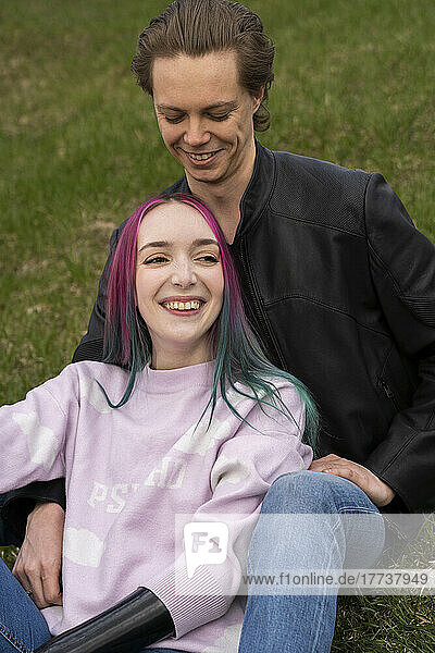Smiling young couple sitting on grass