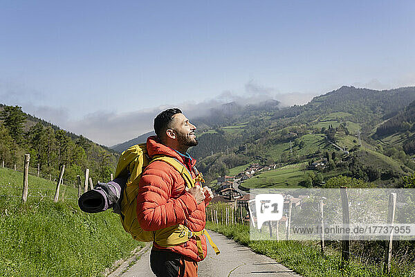 Lächelnder Wanderer mit Rucksack genießt sonnigen Tag