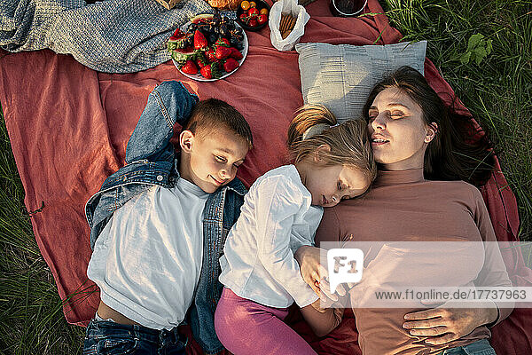 Mutter und Kinder schlafen auf einer Picknickdecke