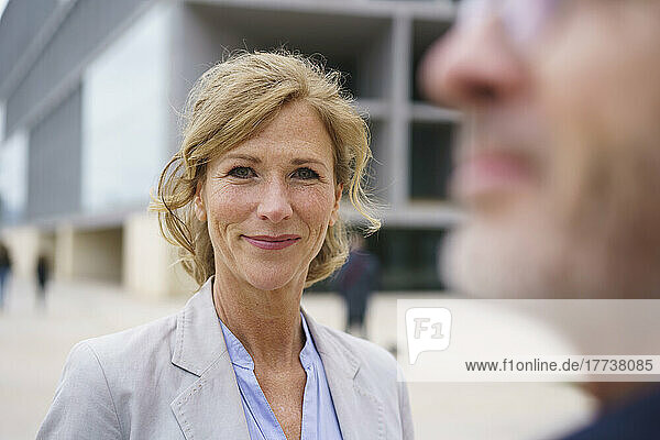 Smiling blond businesswoman in front of businessman