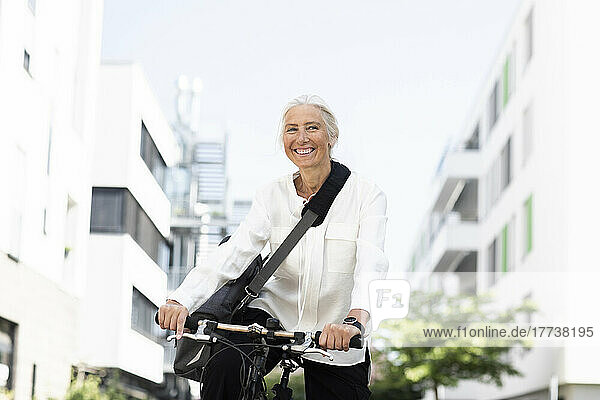 Cheerful mature businesswoman commuting through bicycle