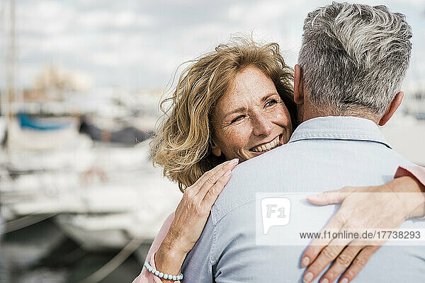 Lächelnde Frau umarmt Mann am Hafen