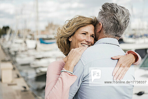 Glückliche Frau umarmt Mann am Hafen