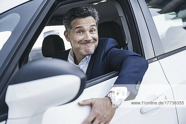 Mature businessman making face sitting in car