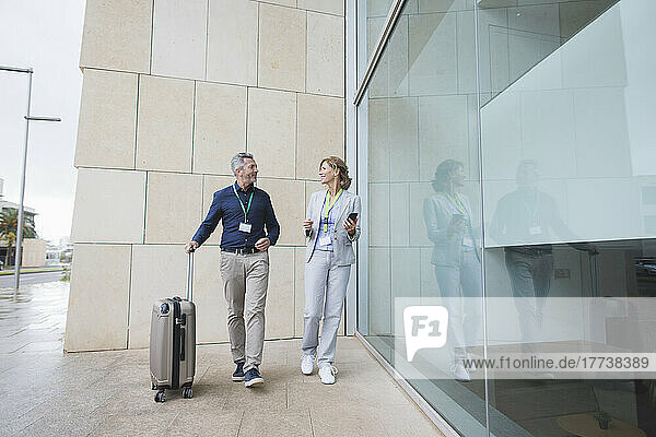 Businessman with suitcase walking by businesswoman