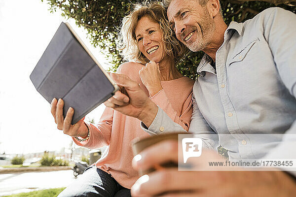 Happy mature couple using tablet computer in park