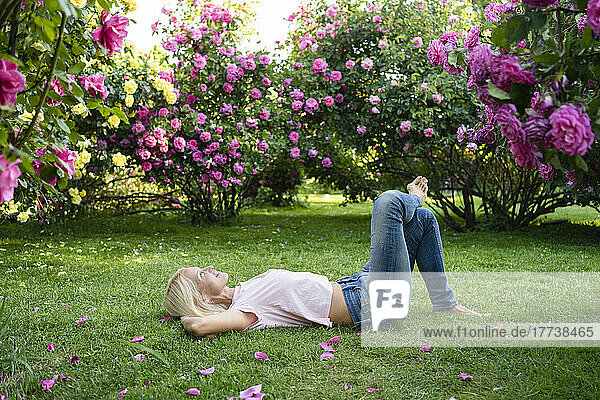 Woman with hands behind head lying on grass at garden