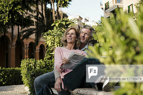 Thoughtful mature couple with newspaper in park