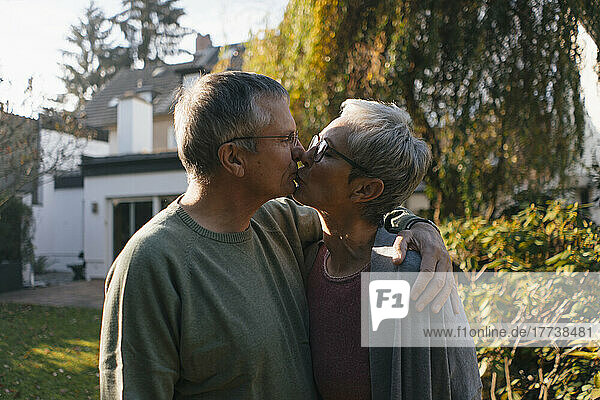 Zärtliches Seniorenpaar umarmt und küsst sich im Garten