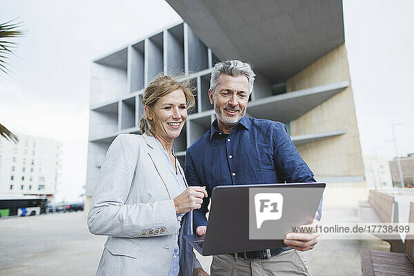 Smiling businessman sharing laptop with businesswoman