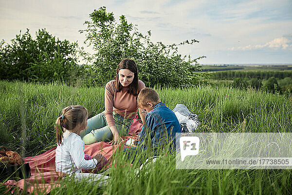 Mutter spricht mit Kindern beim Picknick im Feld