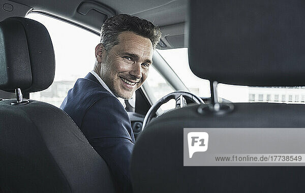 Happy businessman sitting on driver's seat in car
