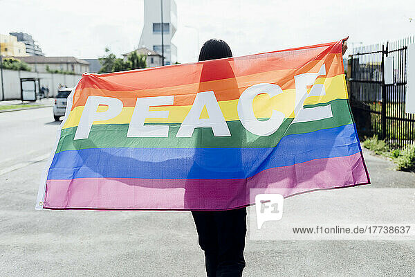 Young woman with peace flag walking on road