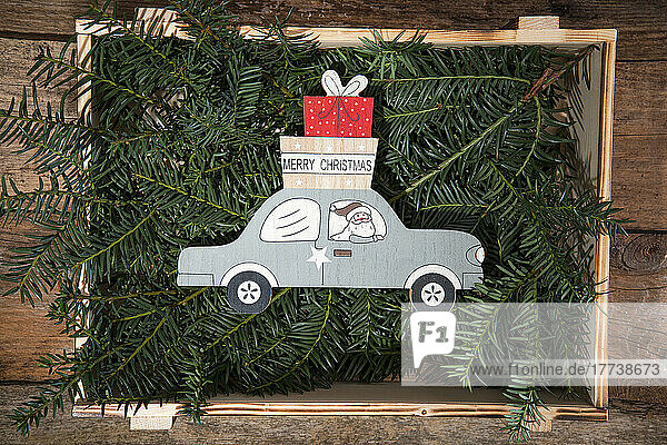Kiste gefüllt mit Nadelbaumzweigen und Weihnachtsdekoration des Weihnachtsmanns  der Geschenke mit dem Auto ausliefert