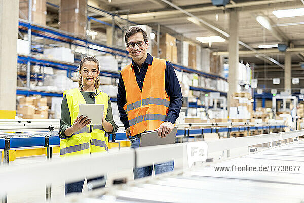 Smiling workers with tablet PC standing together in warehouse