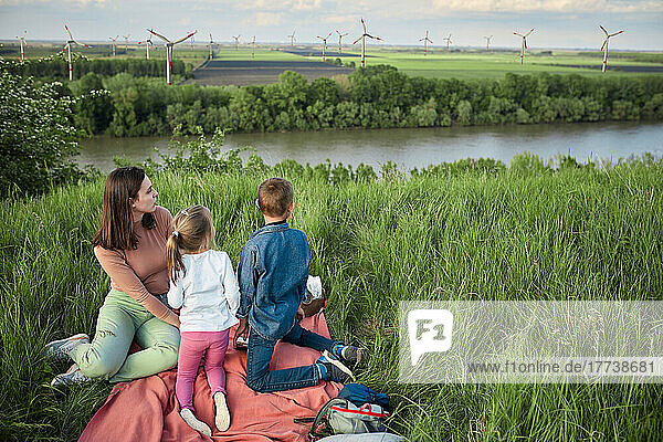 Mother with daughter and son looking at wind turbines in field on weekend