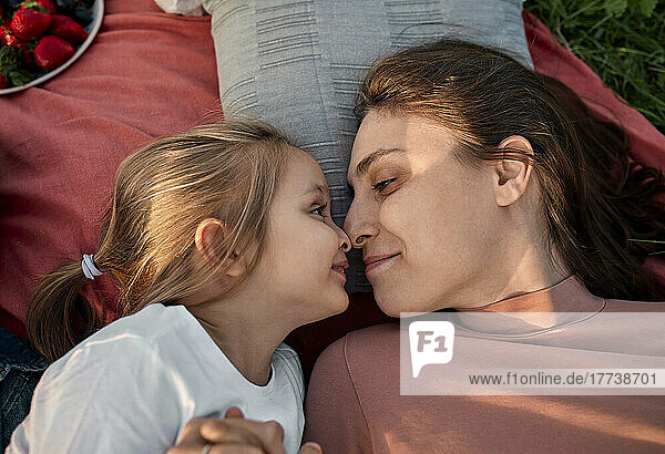 Smiling mother and daughter rubbing noses at picnic in field