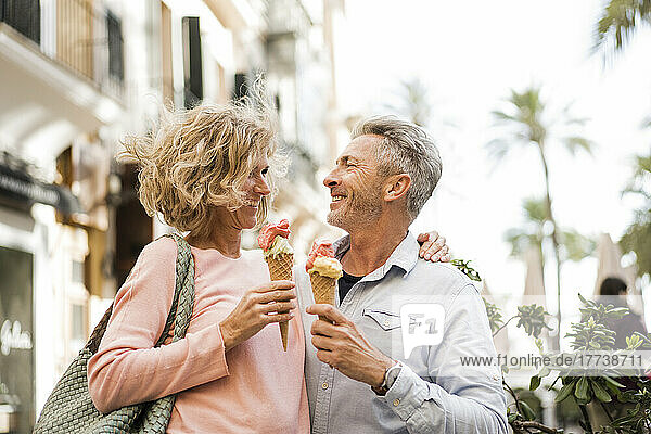Happy mature couple having ice cream in city