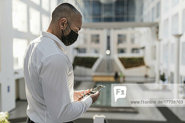 Man using smart phone wearing protective face mask