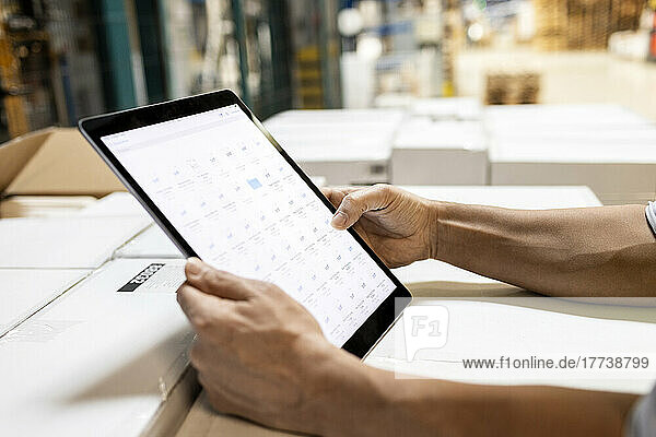 Hands of worker checking inventory on tablet PC in warehouse