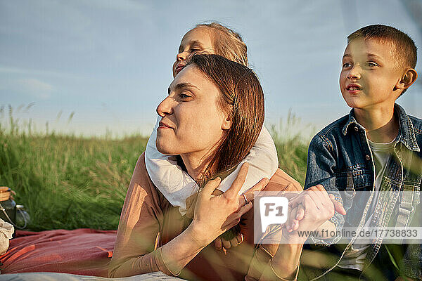Smiling mother and children together in field at picnic