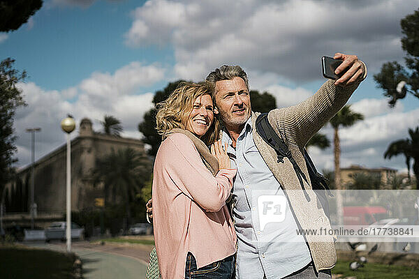 Smiling couple taking selfie on smart phone in city