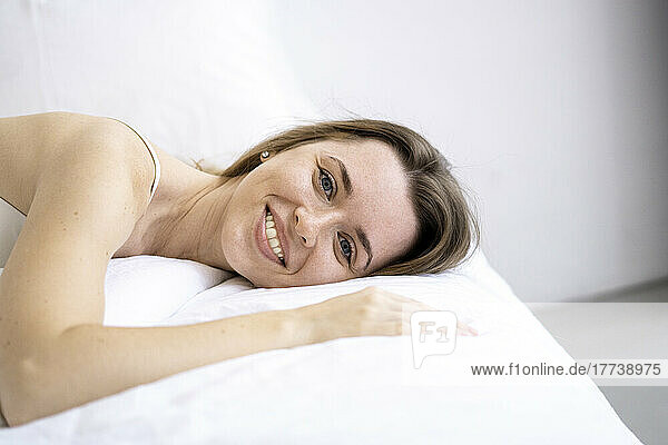 Happy woman lying on bed at home