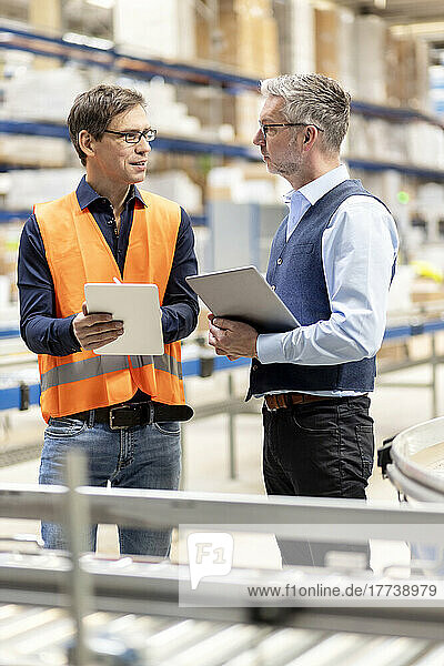 Worker with tablet PC discussing with manager in warehouse