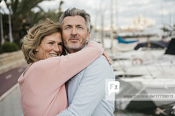 Happy mature woman embracing man at harbor
