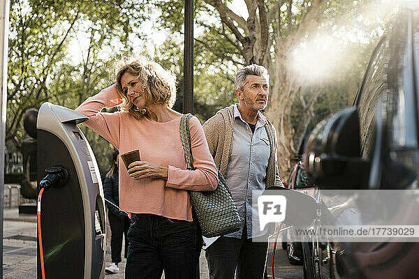 Mature couple with car at charging station