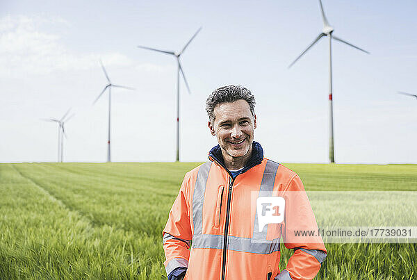 Smiling engineer in reflective clothing standing on field