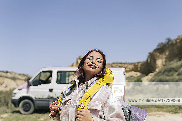 Smiling woman with backpack enjoying sunny day