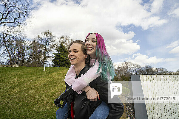 Happy young man giving piggyback ride to girlfriend with dyed hair