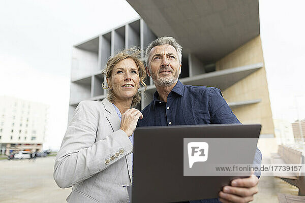 Businessman holding tablet PC standing by businesswoman